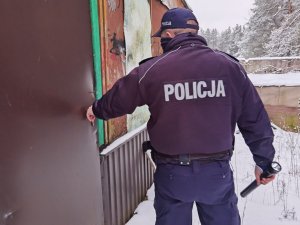 policjant otwiera drzwi pustostanu