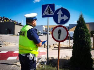 policjant stoi przy znakach drogowych