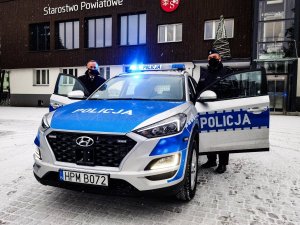 Komendant z Starostą stoi pomiędzy radiowozu