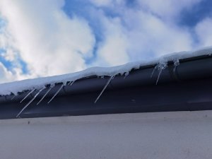 na dachu zalegający śnieg oraz sople z lodu