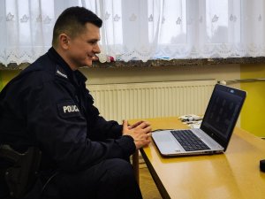 policjant siedzi przed laptopem, prowadzi zajęcia online
