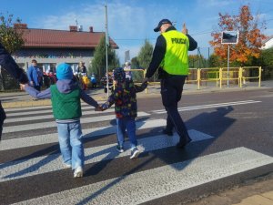 policjanci uczą dzieci jak przechodzić przez przejście dla pieszych