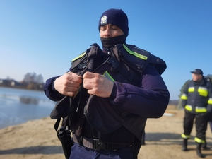 policjant ubiera kamizelkę strażacką