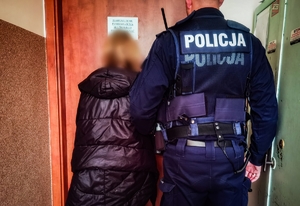 policjant trzyma zatrzymaną osobę