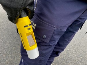 policjant trzyma w ręku żółte urządzenie do badania stanu trzeźwości