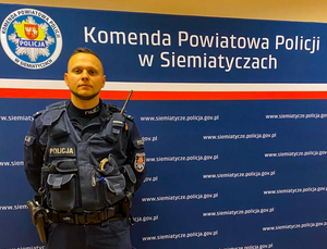 policjant, za nim baner Komendy Powiatowej Policji w Siemiatyczach
