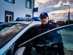 policjant stoi przy radiowozie