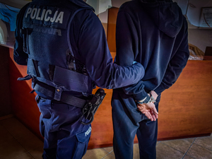 policjant trzyma zatrzymanego mężczyzne