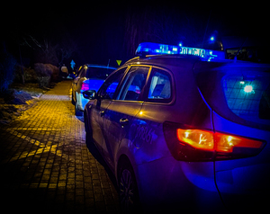 radiowóz z włączonymi światłami uprzywilejowania, w tle samochody