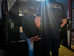 policjant wprowadza do radiowozu zatrzymanego mężczyzne